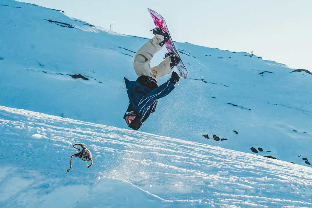 Snowboardåkare tappar mössan under en stor backflip.