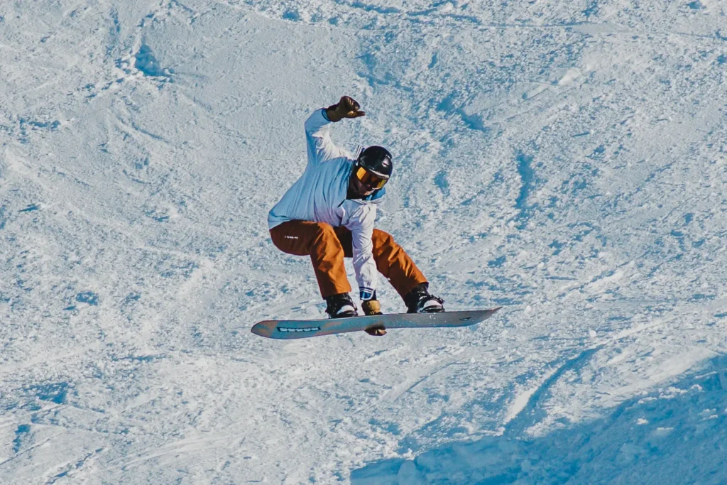 Snowboardåkare hoppar högt och gör en roast beef grab.