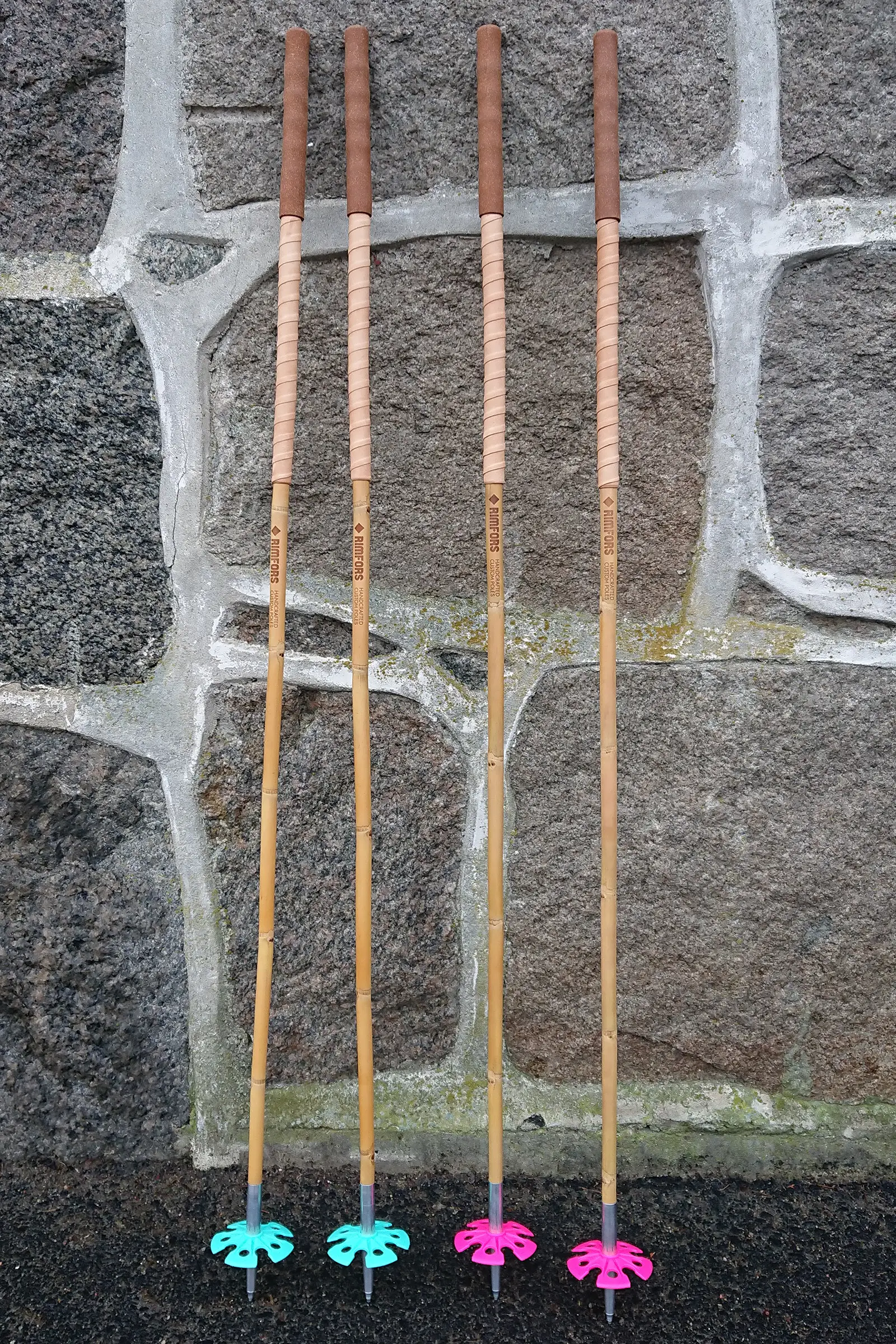 Two pairs of ski touring poles, one turquoise and one pink, inspired by Les Bâtons d'Alain but made of bamboo, with 20 cm cork grip and 25 cm grip extenstions below of bark tanned reindeer leather.