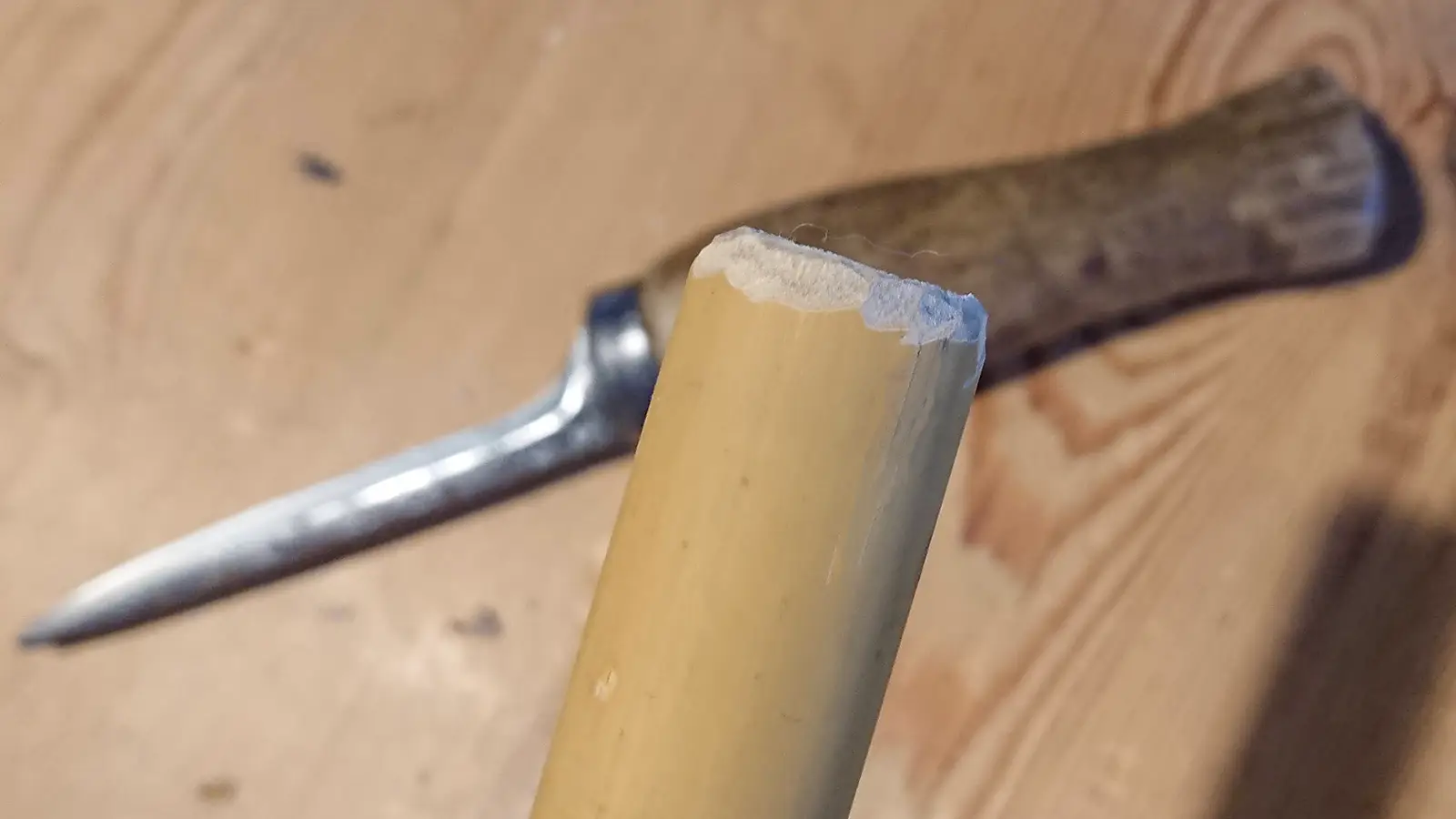 Bambu med avfasad kant och kniv på snickarbänken under.