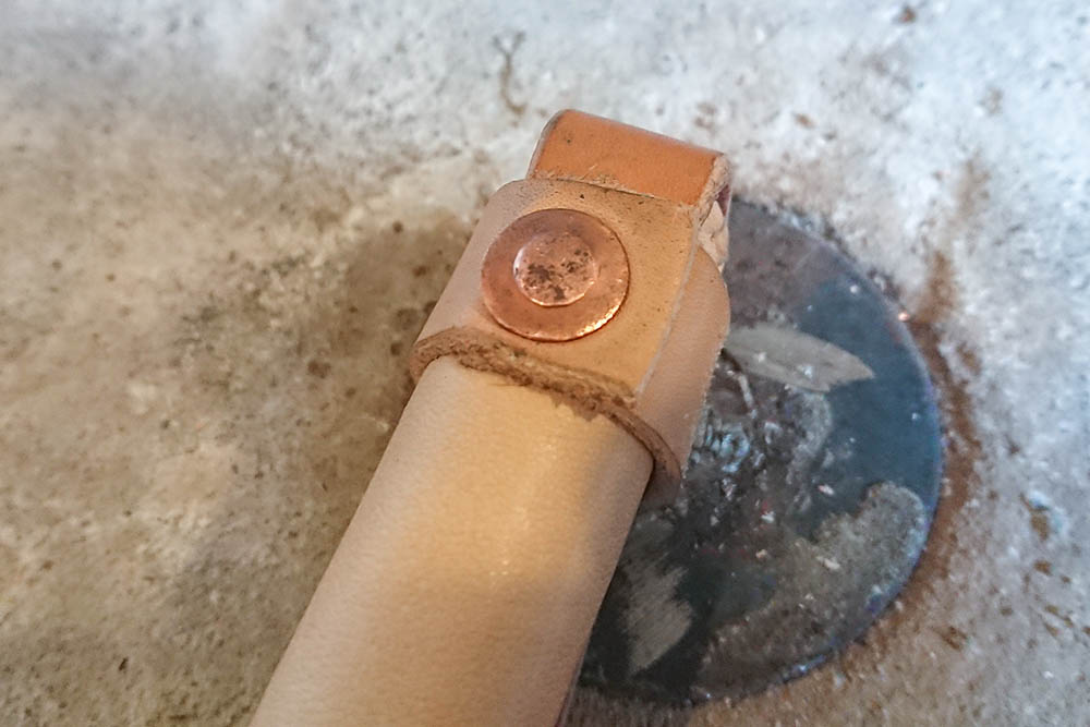 Copper rivet attaching the leather strap on a traditional bamboo ski pole.