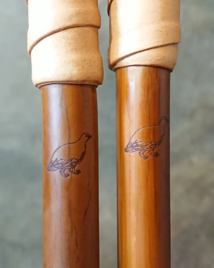 Rock ptarmigan engraved on dark bamboo ski poles.