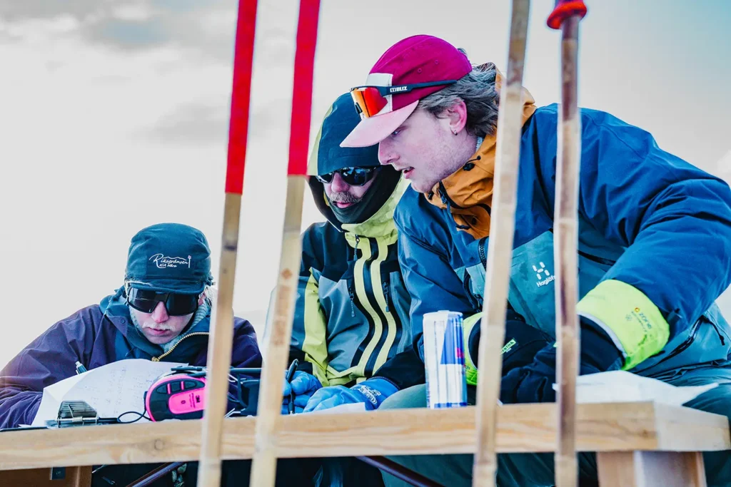 Tre vinterklädda skidåkare agerar domare i en freeridetävling.