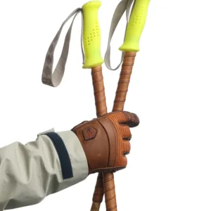 Hand with brown leather glove holds two bamboo ski poles with fluo yellow grips and reindeer leather grip extensions.