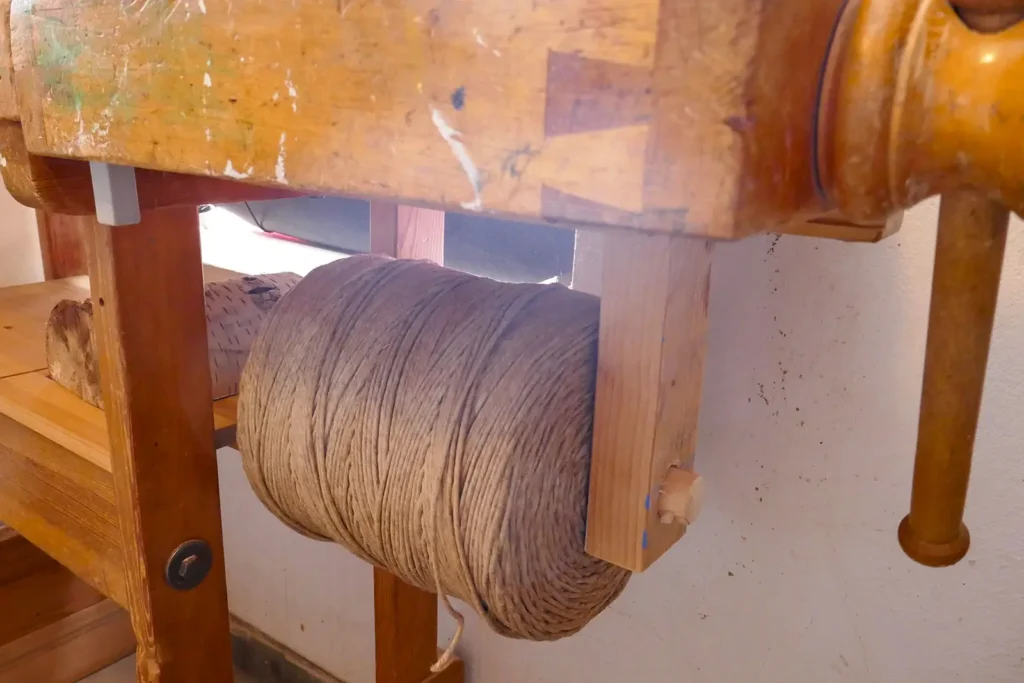 A worn workbench with a roll of hemp cord underneath.