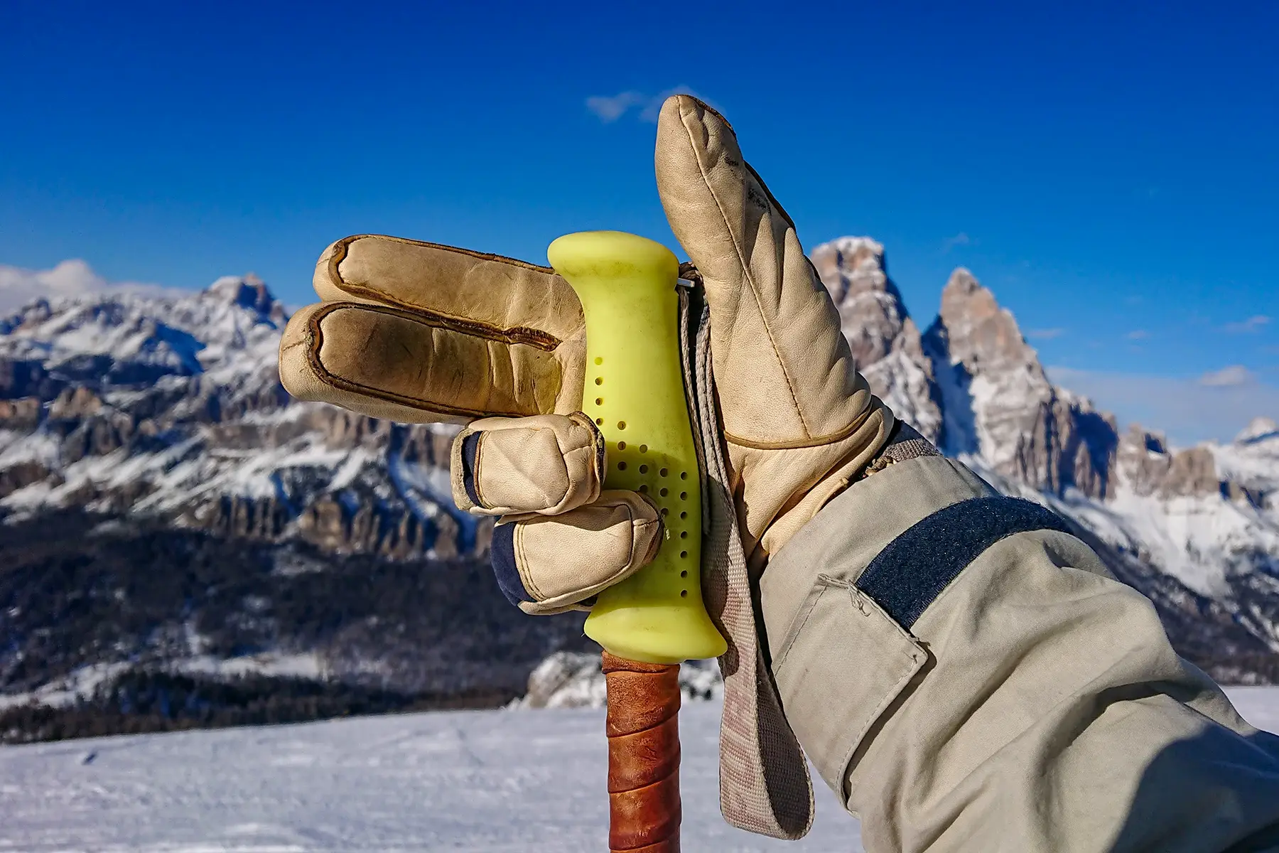 A hand holding a ski pole without the strap around the wrist. The Dolomite mountains in the background.
