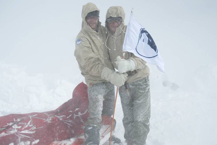 Iglooisterna Fabian Rimfors och Andre Amonsson med Iglooklubbens flagga som fladdrar i stormen vid Marsfjällets fot.