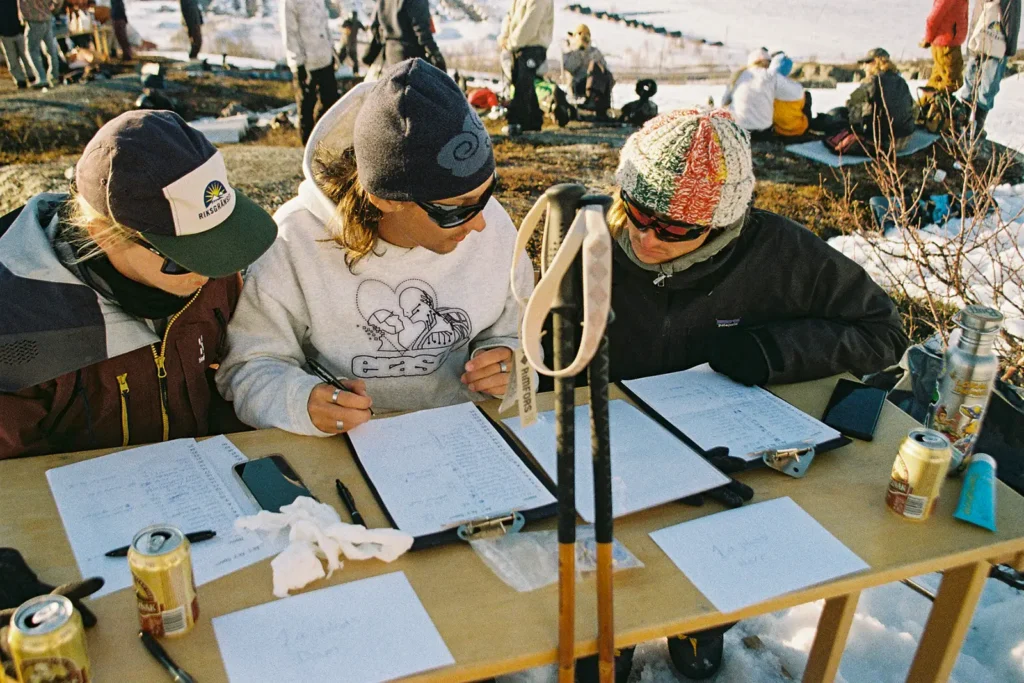 Three guys in sunglasses and beanies confer about how many points a participant should receive.