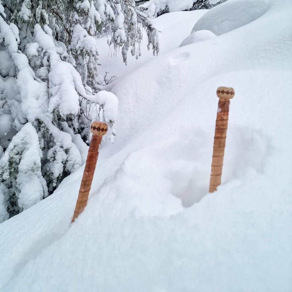 Bambustavar med långt grepp, inspirerade av Les Bâtons d'Alain, djupt nerstuckna i pudersnö.