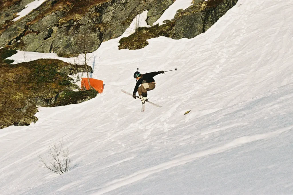 A skier in a black helmet doing a mute grab in steep terrain.