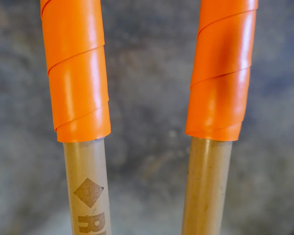 Close-up of bamboo ski poles with orange overgrip tape.