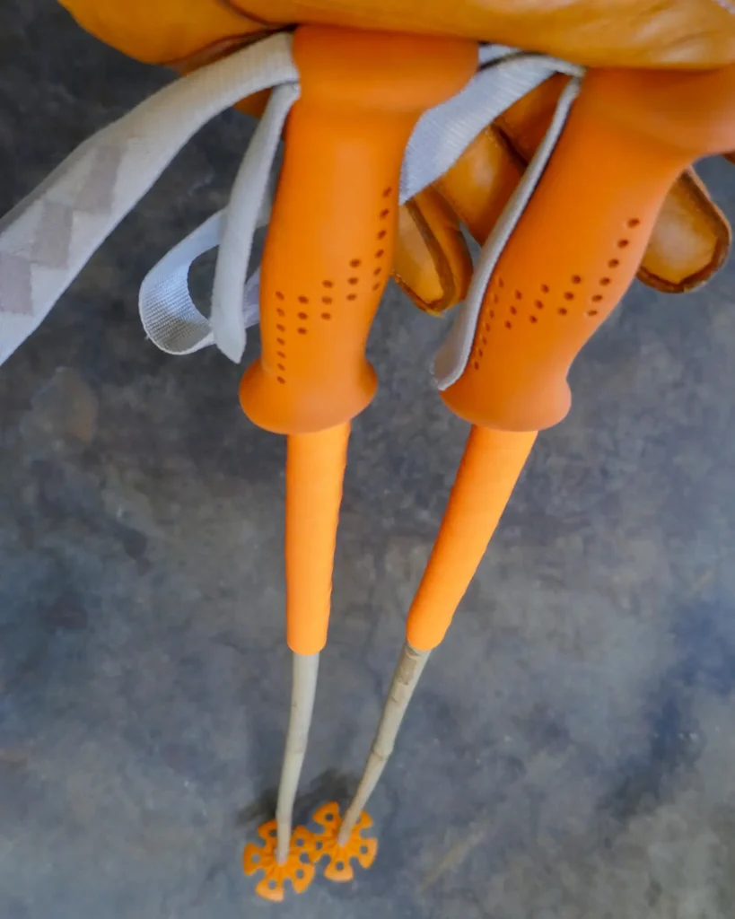 Bamboo ski poles with orange grips and baskets, and long overgrip extensions.