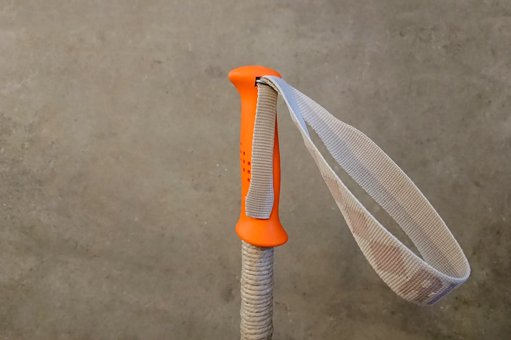 Skidstav med beige handrem och orange handtag. Handremmen är monterad för klassisk turåkning.