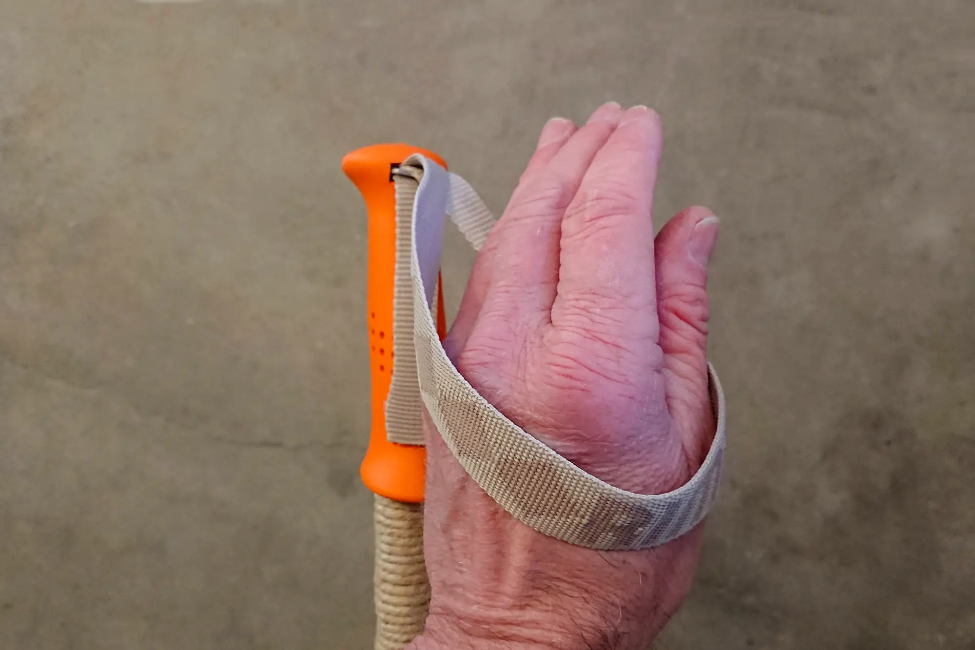 Hand som underifrån trär sig genom en handrem på en skidstav.