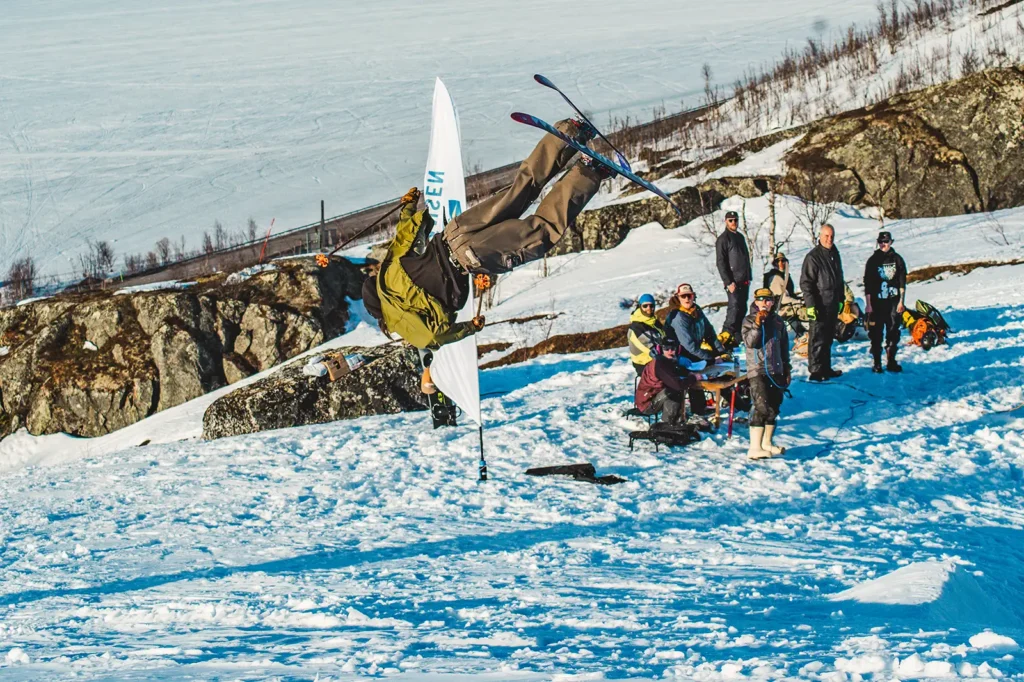 Telemarksåkare gör en backflip vid målgång i freeridetävling.