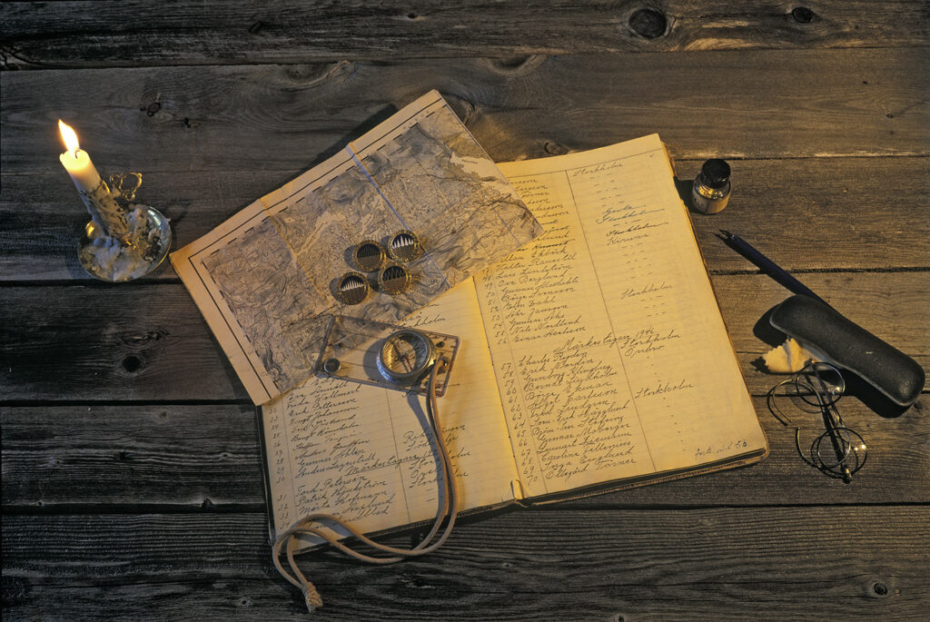 Riksgränsens toppmärkesbok med karta, toppmärken, kompass och levande ljus.