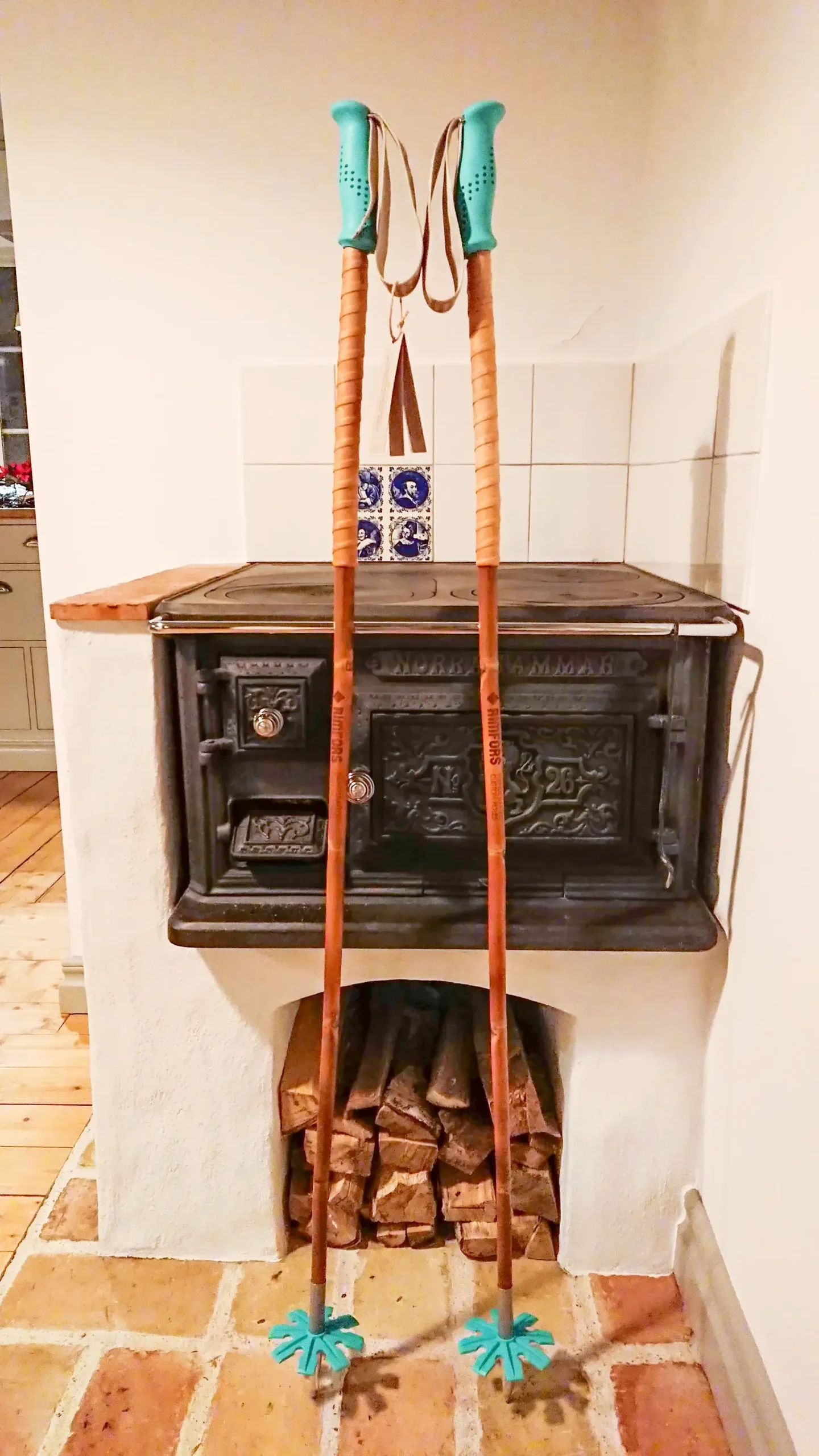 Bamboo ski poles with turquoise grips and baskets in front of a cast iron stove.